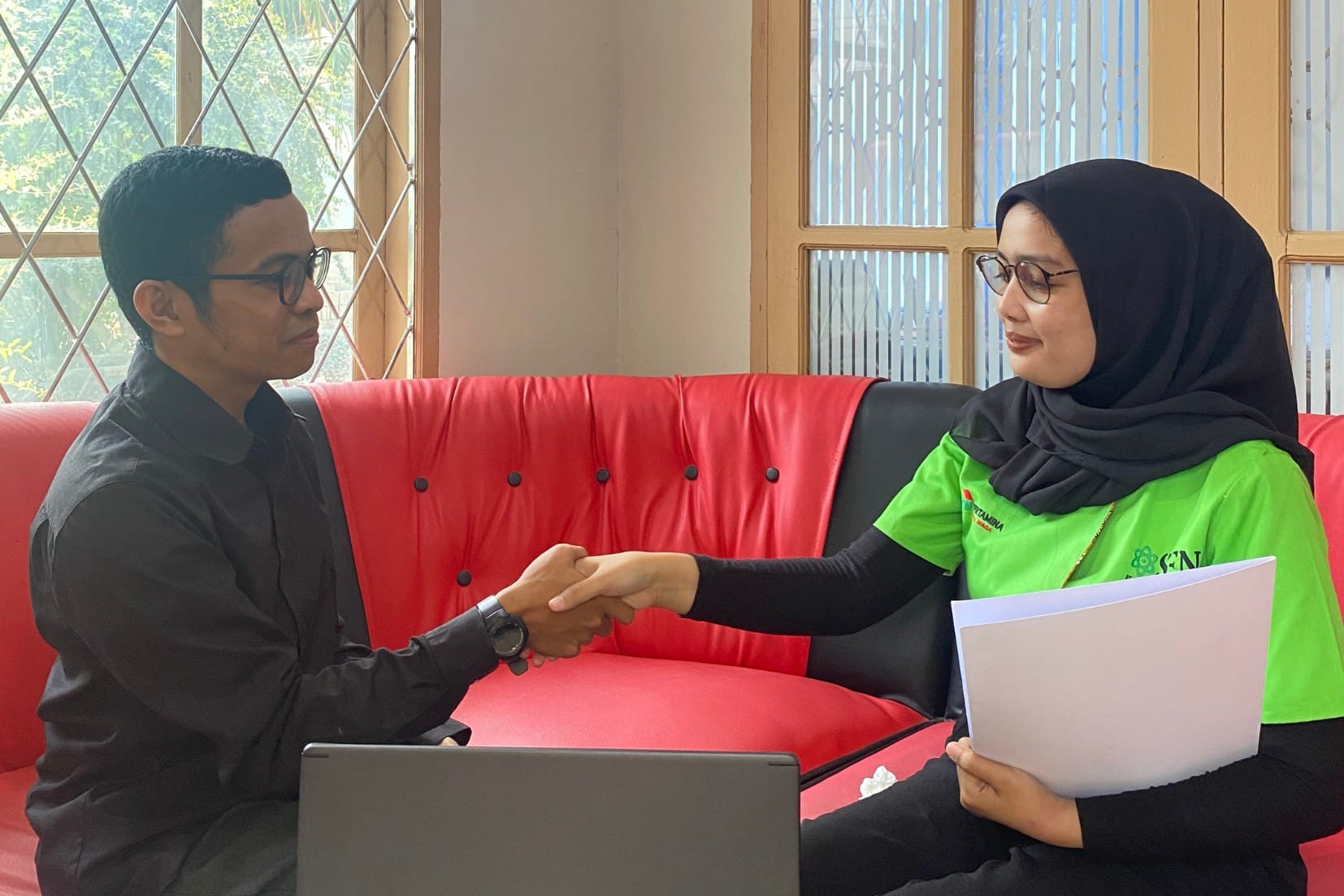Rekan kerja Adiguna berjabat tangan di kantor